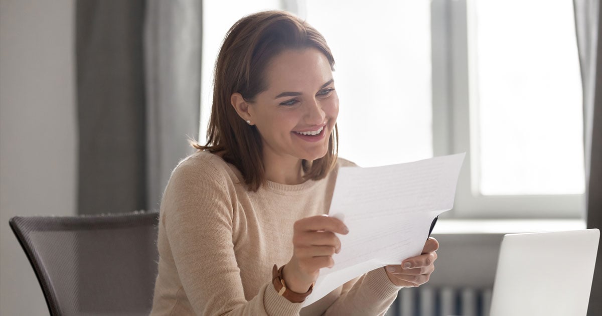 Happy woman reading piece of paper