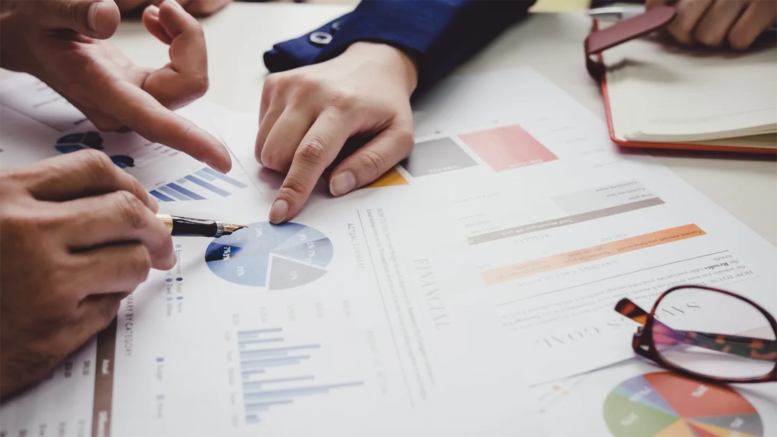 Advisors pointing to pie charts and KPI reports while reviewing an advisory practice valuation